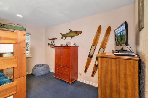 Cozy bedroom with bunk beds, wooden furniture, and decor featuring fishing and skiing themes on the walls.