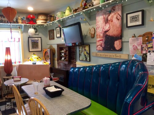 A cozy diner with colorful decor, a blue booth, a checkered table, and whimsical art on the walls.