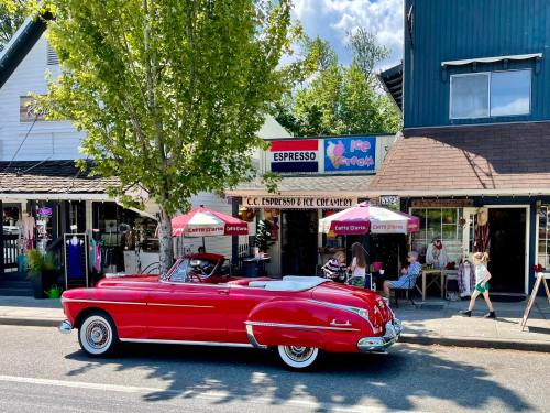 A bright red vintage convertible parked in front of an espresso and ice cream shop on a sunny day.