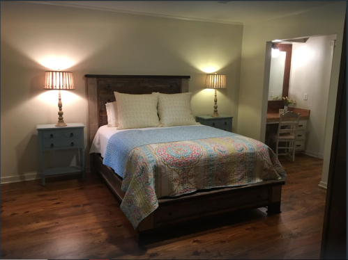 Cozy bedroom featuring a wooden bed, colorful quilt, nightstands, and warm lighting.