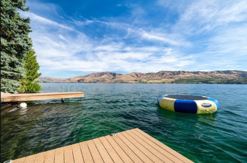 A serene lake view with mountains in the background and a colorful inflatable float on the water.