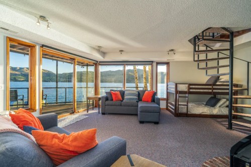 Cozy living room with lake views, featuring a spiral staircase, comfortable seating, and bright orange pillows.