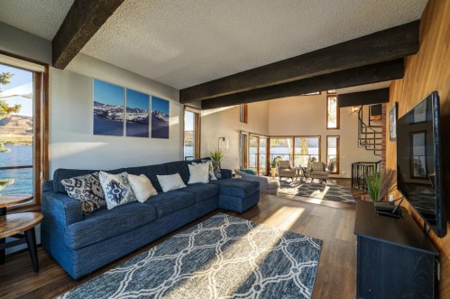 Cozy living room with a blue sofa, large windows, and a view of the lake, featuring modern decor and natural light.