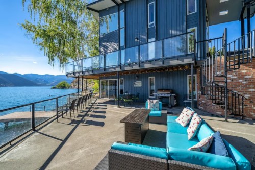 Modern lakeside home with a spacious patio, outdoor seating, and stunning water views.