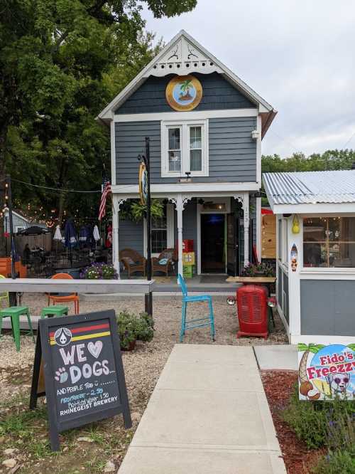 A charming blue building with a sign reading "We ❤️ Dogs" and outdoor seating at a brewery.