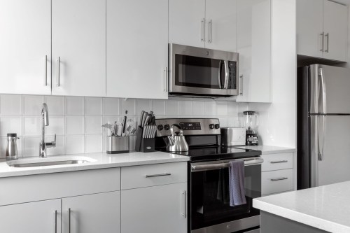 Modern kitchen with stainless steel appliances, white cabinets, and a sleek countertop.