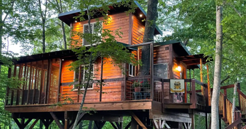 A cozy wooden treehouse nestled among trees, featuring multiple levels and warm lighting.
