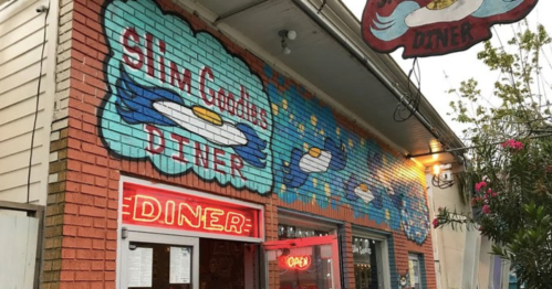 Colorful exterior of Slim Goodies Diner, featuring murals of eggs and a bright "OPEN" sign.