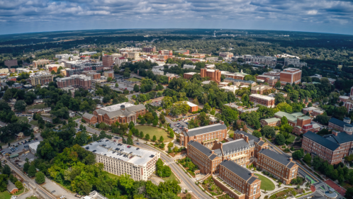 An aerial view of Athens, Georgia, showcasing the downtown area with lots of brick buildings and a blue summer sky overhead.
