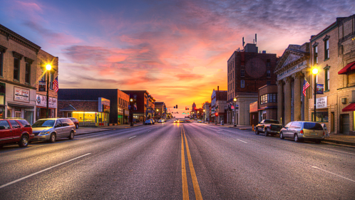 Looking down a main street at dusk in Hannibal, Missouri with a focus on the wide street and sunset sky overhead.