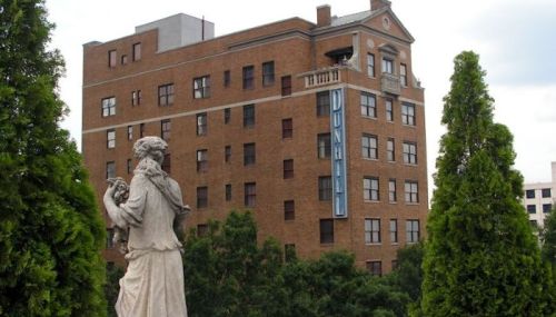 A statue in the foreground with a historic brick building featuring a "Dunhill" sign in the background.