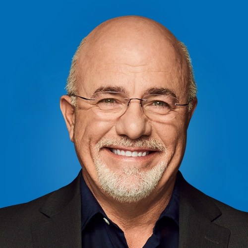 A smiling man with glasses and a bald head, wearing a black suit against a blue background.