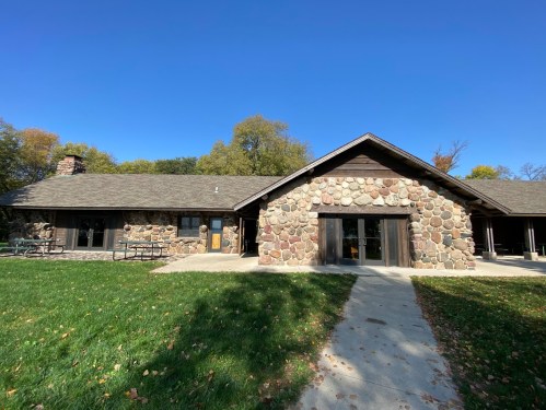A rustic stone and wood building with a grassy area in front, under a clear blue sky.