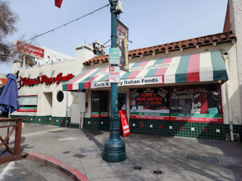 Exterior of Flippa's Pizza Grotto, featuring a striped awning and signage for Italian food, on a sunny street corner.
