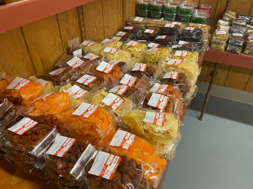 A display of colorful packaged snacks and candies arranged neatly on a wooden shelf.