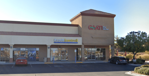 Exterior view of a commercial building featuring a Thai restaurant and a tech store, with parking in front.