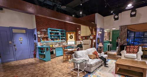 A cozy living room set with colorful furniture, a kitchen area, and decorative elements, resembling a home interior.