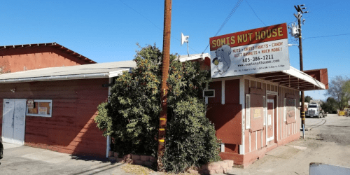 Exterior of Somis Nut House, a small red building with a sign advertising nuts, candy, and other snacks.