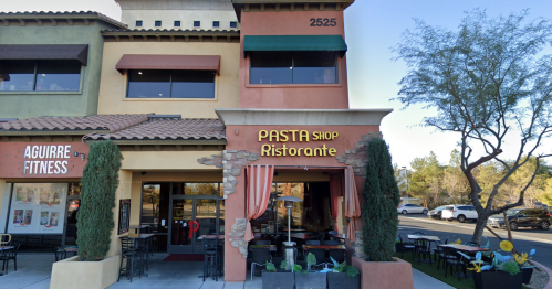 Exterior of a pasta restaurant with a sign reading "PASTA Shop Ristorante," featuring outdoor seating and a sunny day.