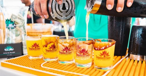 A bartender pours drinks into shot glasses at a vibrant bar, with money and a sign for "Tequila & Taco" in the background.