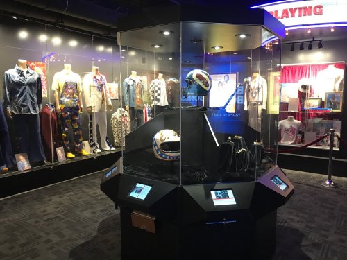 Display case featuring a helmet and clothing from a sports exhibit, surrounded by mannequins in vintage outfits.