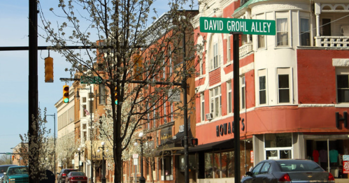 Street view featuring a sign for "David Grohl Alley" alongside historic buildings and blooming trees.