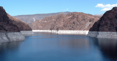 A serene lake surrounded by rocky mountains under a clear blue sky, reflecting the landscape in calm waters.