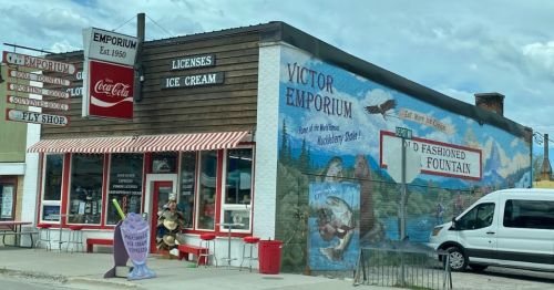 A colorful storefront with a mural, featuring an ice cream shop and vintage signage in a small town.