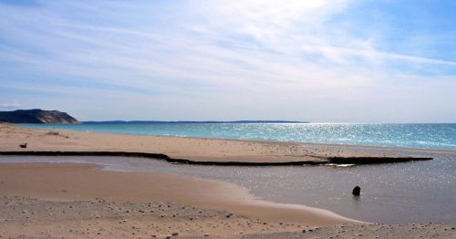 A serene beach scene with gentle waves, soft sand, and a clear blue sky, creating a tranquil coastal atmosphere.
