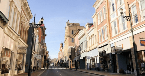 A quiet street lined with historic buildings and shops under a clear blue sky.