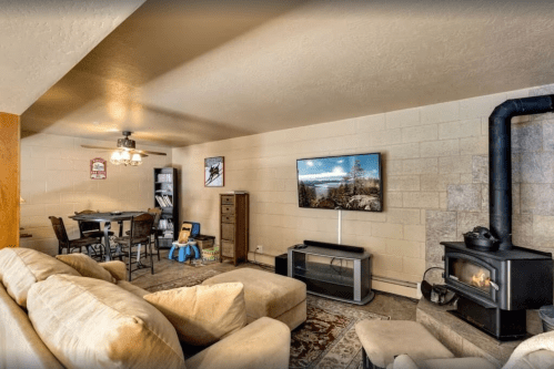 Cozy living space with a sofa, TV, dining area, and a wood stove, featuring warm lighting and a rustic decor.
