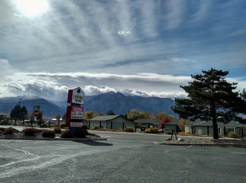 A scenic view of mountains under a cloudy sky, with a sign for a local business in the foreground.