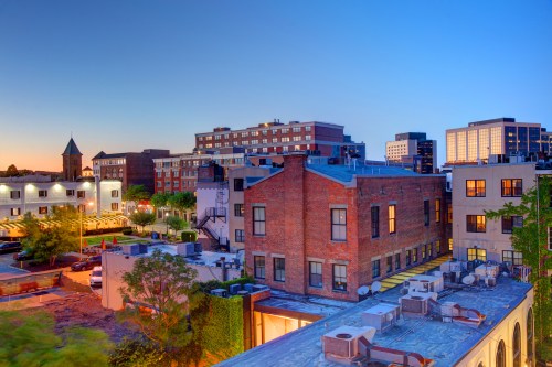 Cityscape at dusk featuring brick buildings, modern architecture, and a clear blue sky.