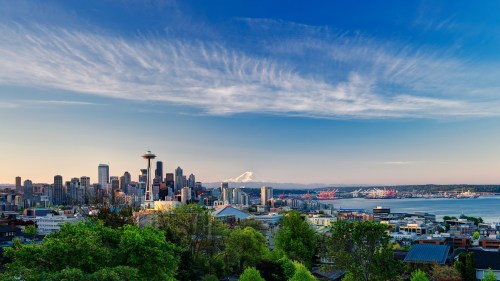 A panoramic view of Seattle's skyline with Mount Rainier in the background and a clear blue sky.