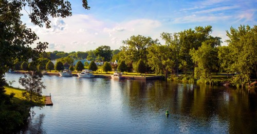 hudson river in upstate new york on a partly cloudy day with green trees and sailboats nearby