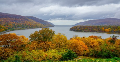 the hudson river on a cloudy day with autumn trees all around
