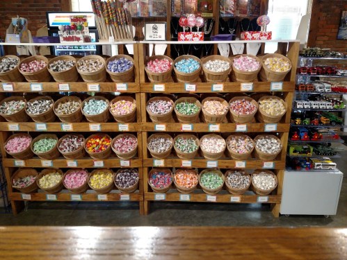 A colorful display of candy in baskets on wooden shelves, with various sweets arranged neatly.