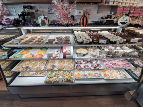 A display case filled with various cookies, cupcakes, and decorated treats in a bakery.