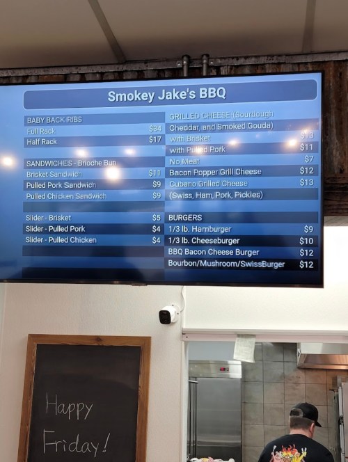 Menu board at Smokey Jake's BBQ displaying prices for ribs, sandwiches, and burgers.