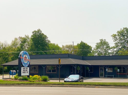A black building with a sign reading "The Boss" and a parked car in front, surrounded by greenery.
