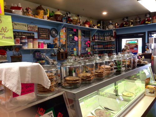 A colorful ice cream shop display with jars of cookies, a chalkboard menu, and various decorations on the walls.