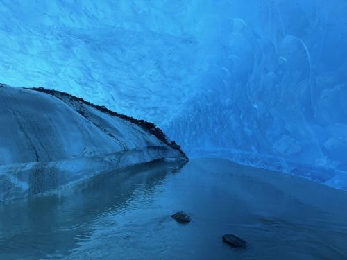 A serene icy cave with blue hues, featuring a calm water surface and rocky formations.