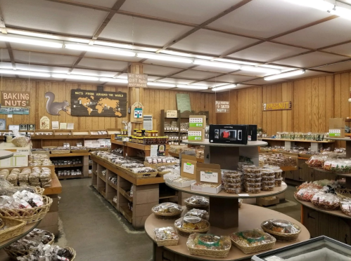 A cozy store interior filled with shelves of various nuts and snacks, featuring wooden decor and organized displays.