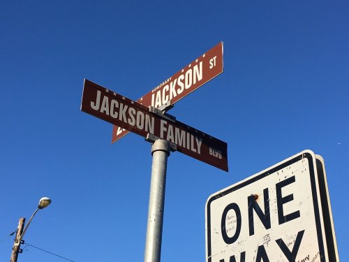 Street signs for Jackson Street and Jackson Family Boulevard against a clear blue sky. One-way sign visible below.
