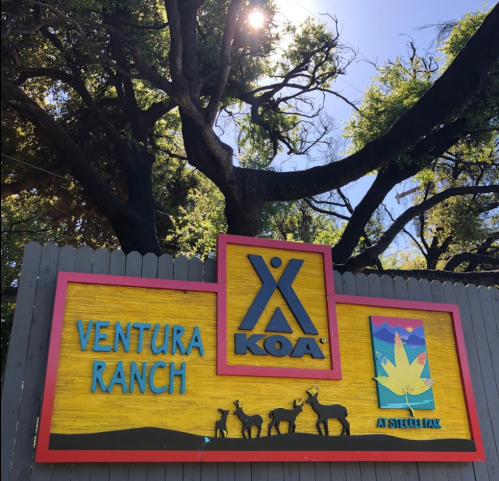Colorful sign for Ventura Ranch KOA at Sierra Park, featuring trees and animal silhouettes under a bright sun.