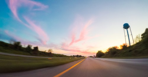 Pink clouds color the sky above a highway in a Kansas town.