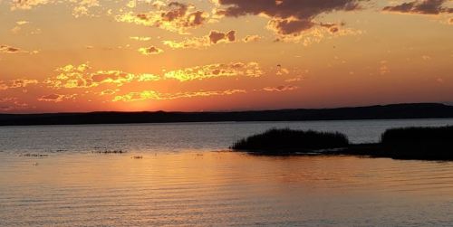 A serene sunset over a calm lake, with vibrant orange and yellow hues reflecting on the water's surface.