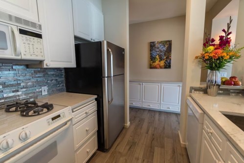 Modern kitchen with white cabinets, stainless steel appliances, and a colorful floral arrangement on the counter.