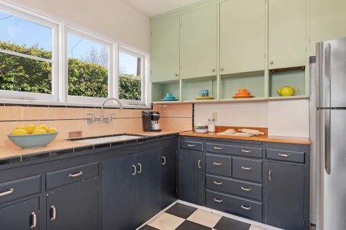 A bright kitchen with green cabinets, black and white checkered floor, and a bowl of lemons on the counter.