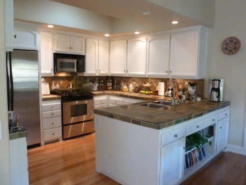 Bright kitchen with white cabinets, stainless steel appliances, and a stone countertop, featuring a cozy dining area.